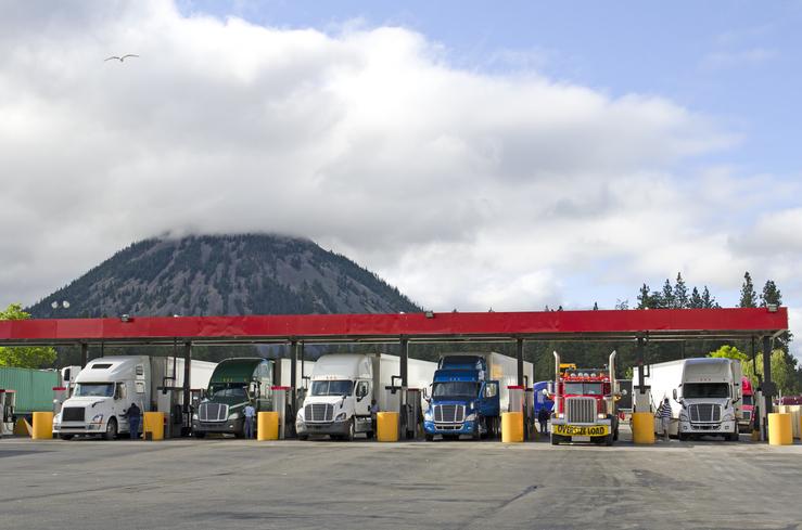 Several semi-trucks refuel at a fueling station in California