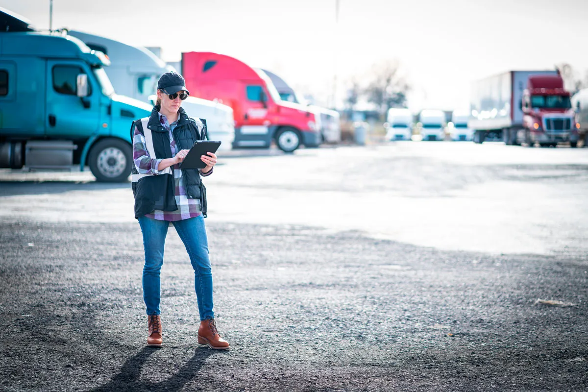 Truck dispatcher walking through a truck yard while working on a digital tablet