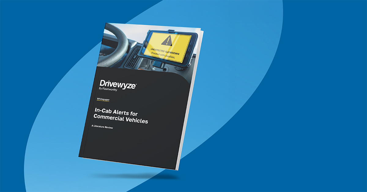 A booklet titled In-Cab Alerts for Commercial Vehicles: A Research Review by Drivewyze is displayed against a blue background, featuring an image of a truck cab interior with a warning alert on a tablet—highlighting Smart Roadways technology.