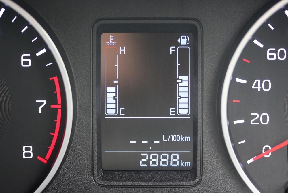 Digital car dashboard display showing engine temperature gauge, fuel gauge, average fuel consumption, and an odometer reading of 2888 kilometers—features that support driver satisfaction and truck driver retention. Analog speedometer and tachometer partially visible on either side.
