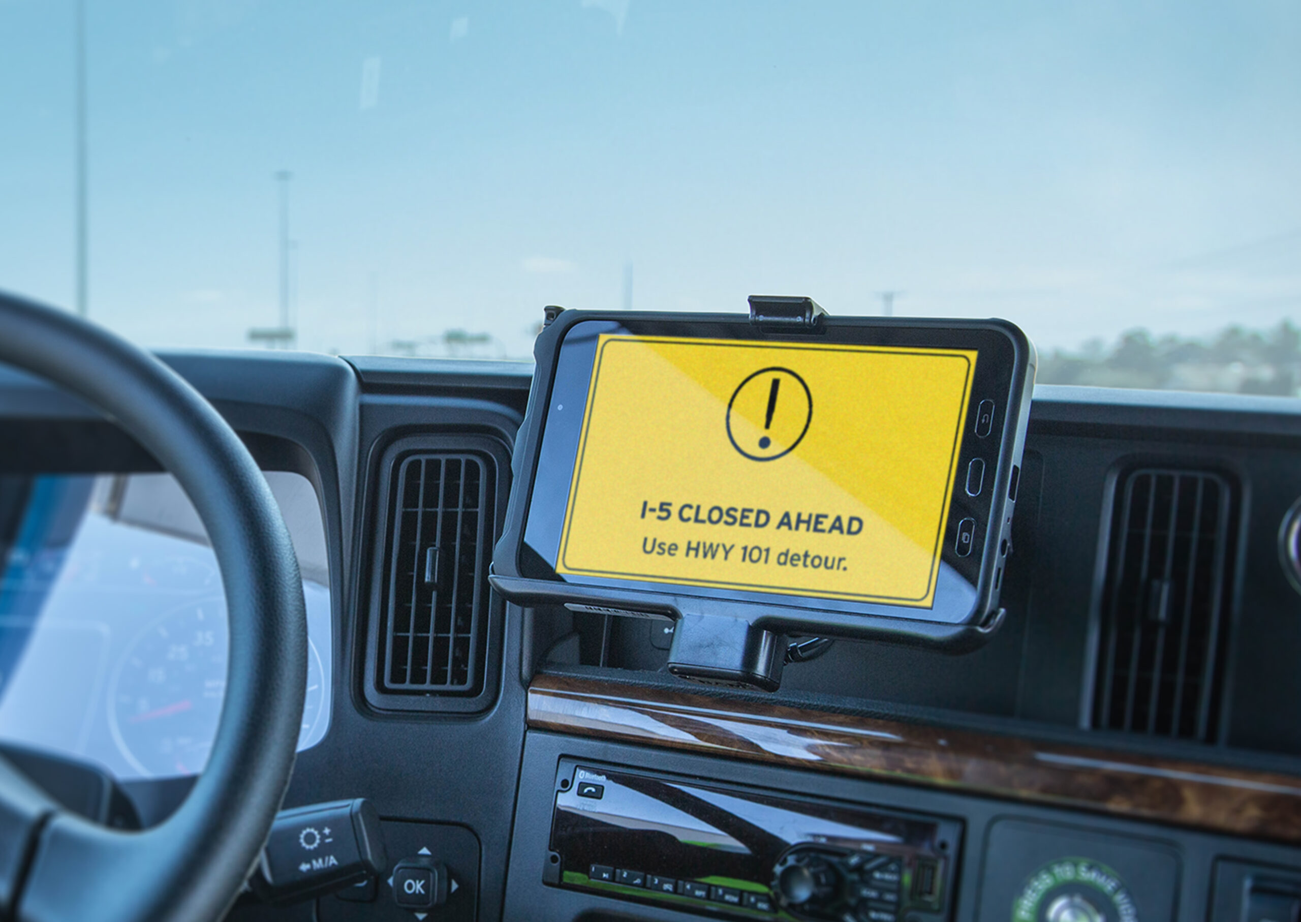 “Drivewyze notification on a truck dashboard alerts driver to I-5 closure with HWY 101 detour.”